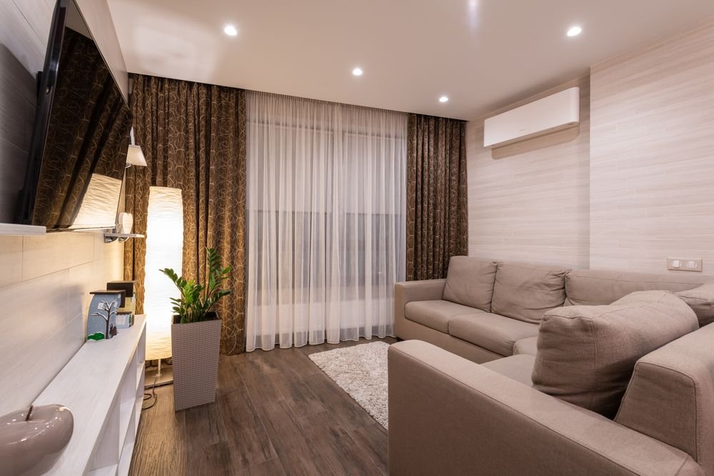 Sala familiar cálida con cortinas dobles: sheer blanco y drape decorativo