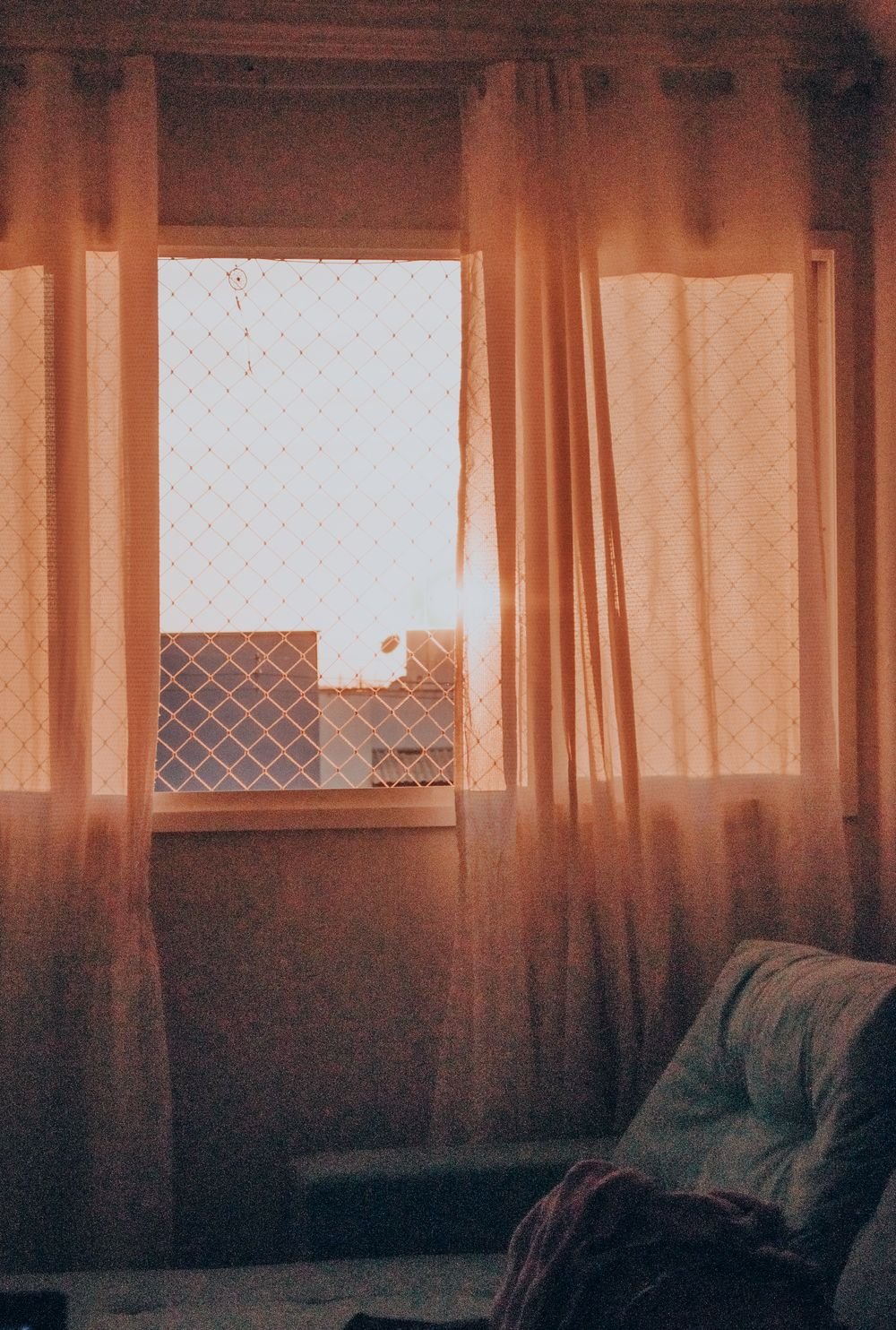 Ventana iluminada por el sol con cortinas translúcidas
