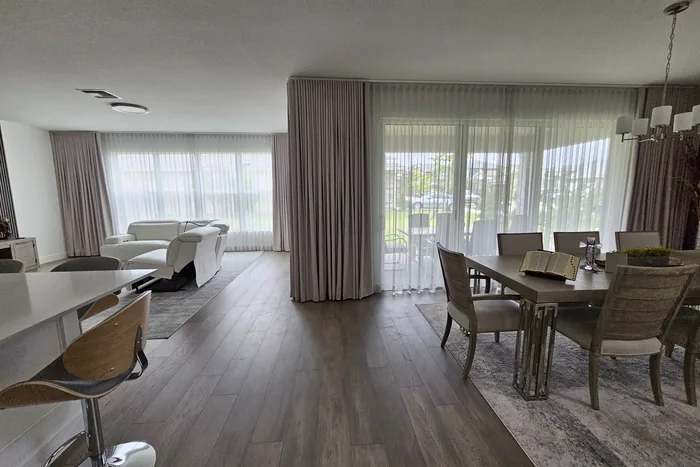 Comedor y sala con ventanales de piso a techo y cortinas sheer y drape