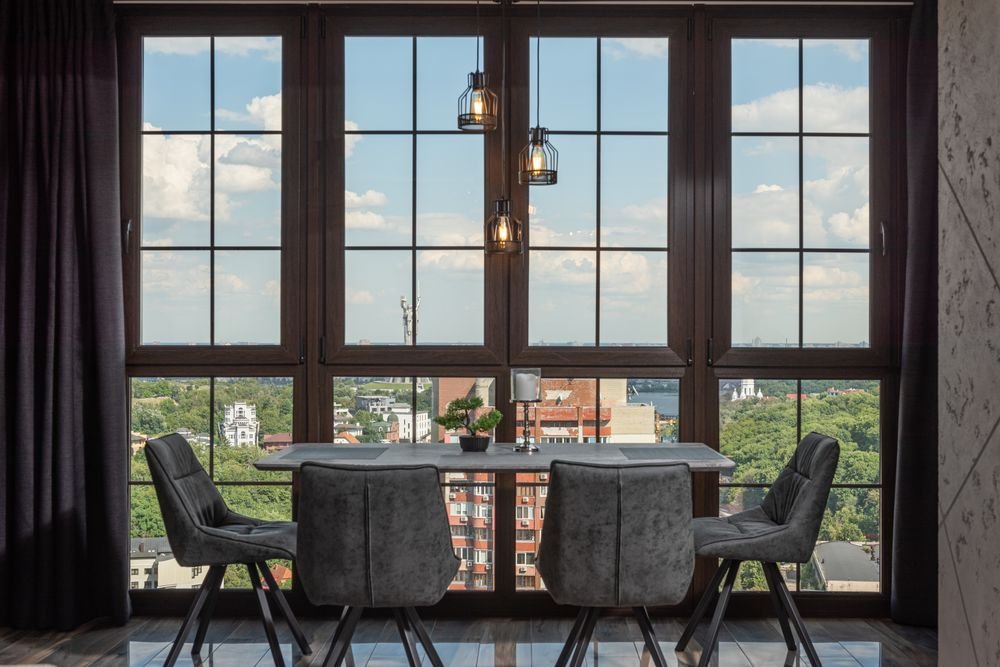 Comedor de lujo con ventanales de piso a techo y cortinas oscuras